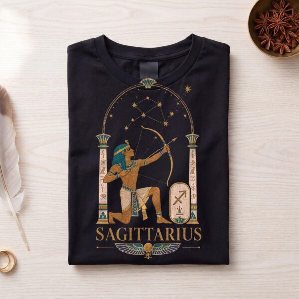 Black Sagittarius Ancient Egypt zodiac T-shirt folded flat on white wood with a feather and star anise