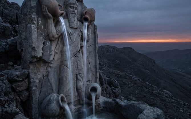 Gula, the Great One: a colossal weathered stone figure of a bearded Mesopotamian water-bearer standing astride a dark mountain ridge at dusk, two great vases raised overhead pouring bright streams of rain down toward the earth, two more vases at his