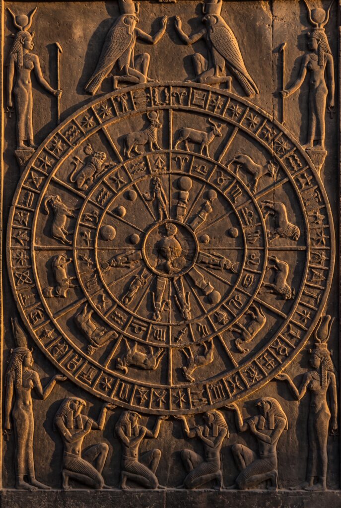 The Dendera zodiac: the circular sandstone sky-map relief from the Temple of Hathor, seen straight on and filling the whole frame edge to edge. The round disk is packed with carved Egyptian figures of the zodiac signs and planets, a ring of decan sta