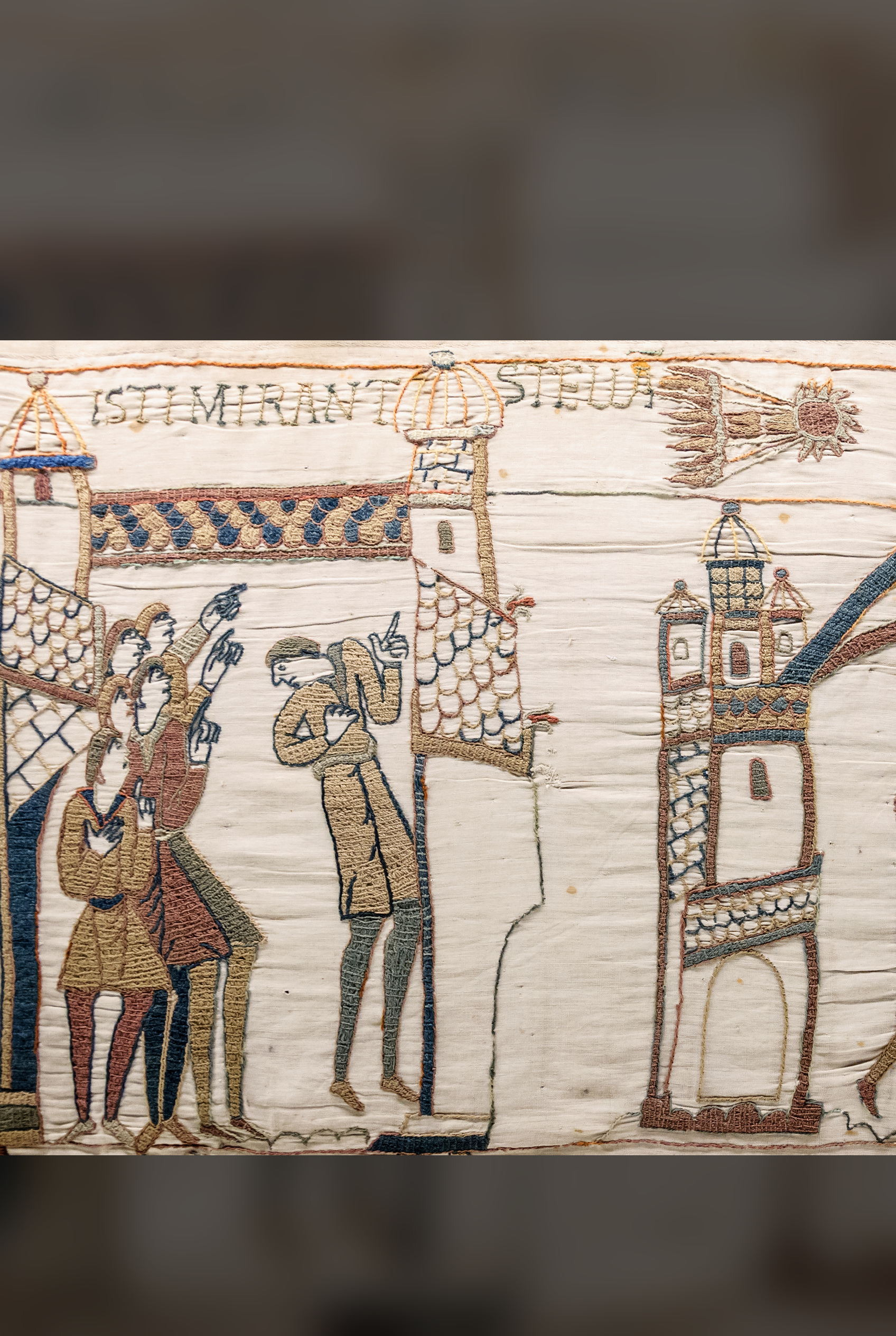 Embroidered men pointing up at a comet with a fiery tail